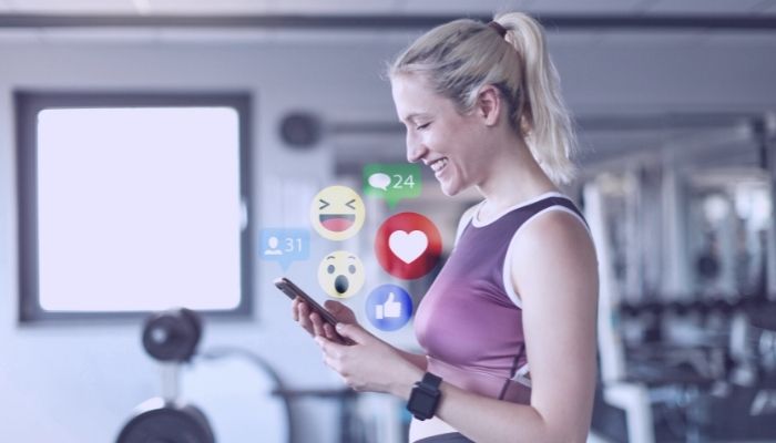 woman at gym looking at social media on smartphone